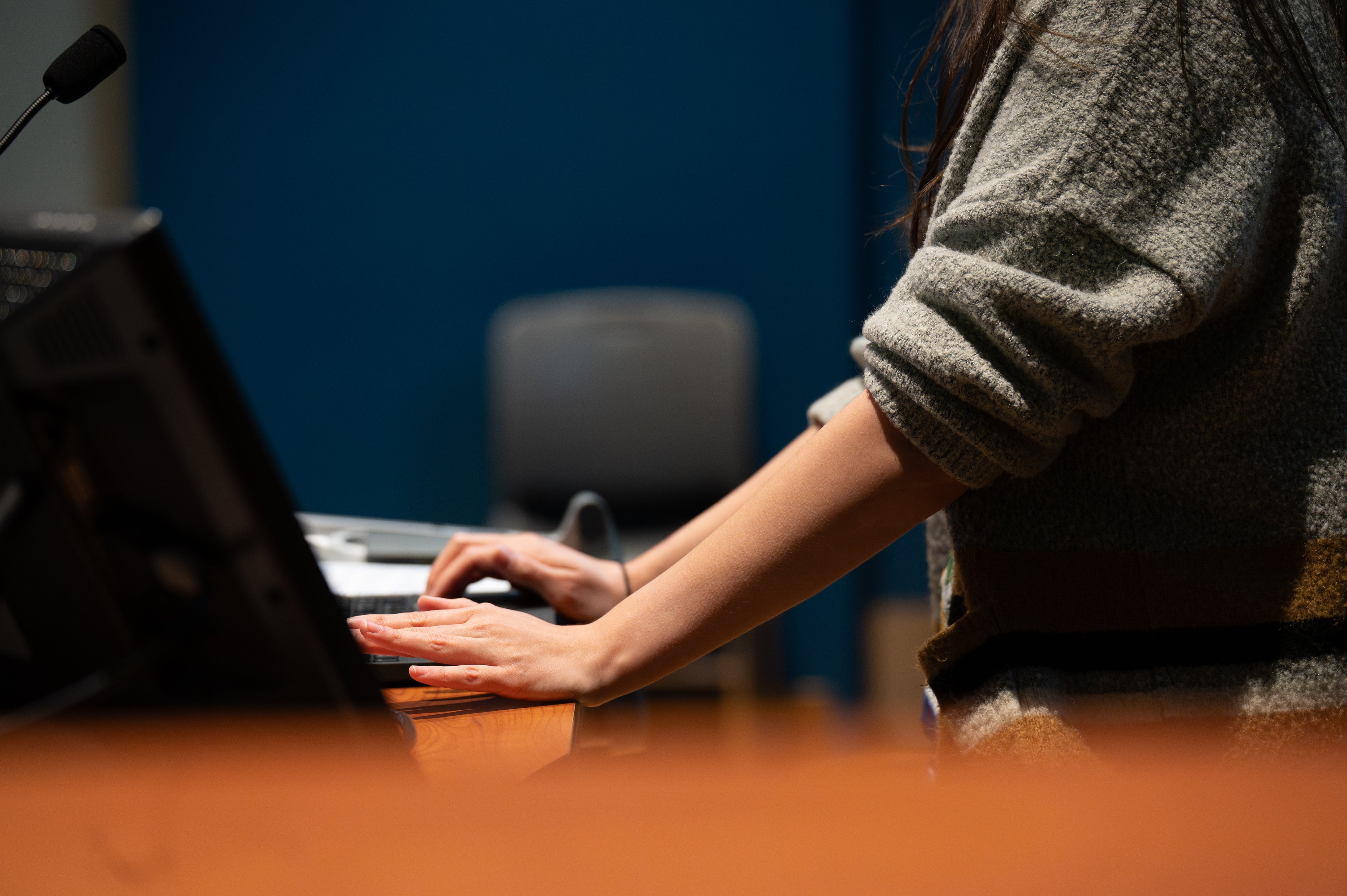 Person typing on a laptop at a desk with a blurred background
